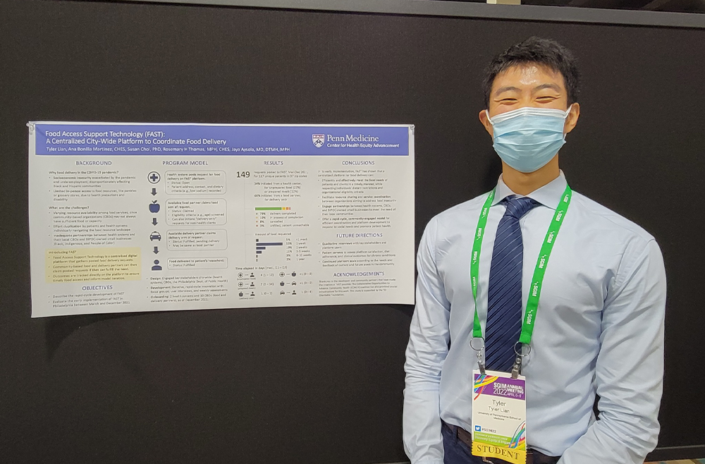 Image of Tyler Lian at a conference, standing to the right of a poster showcasing his team’s work on the Food Access Support Technology (FAST) project
